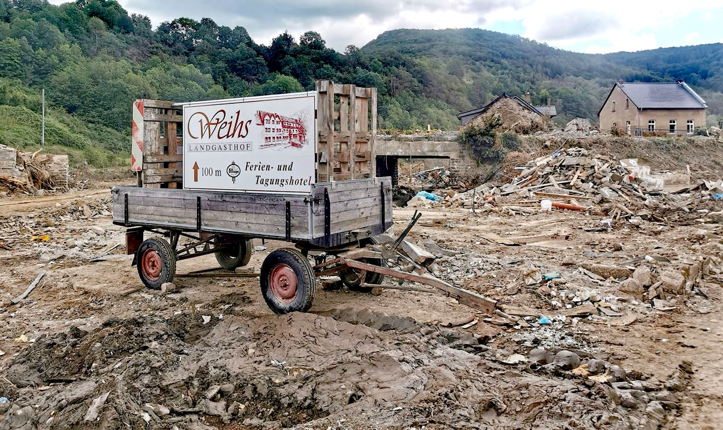 Ein Amhänger mit dem Schild von Landgasthof Weihs steht 2021 in den Trümmern, die die Flutkatastrohe hinterlassen hat.
